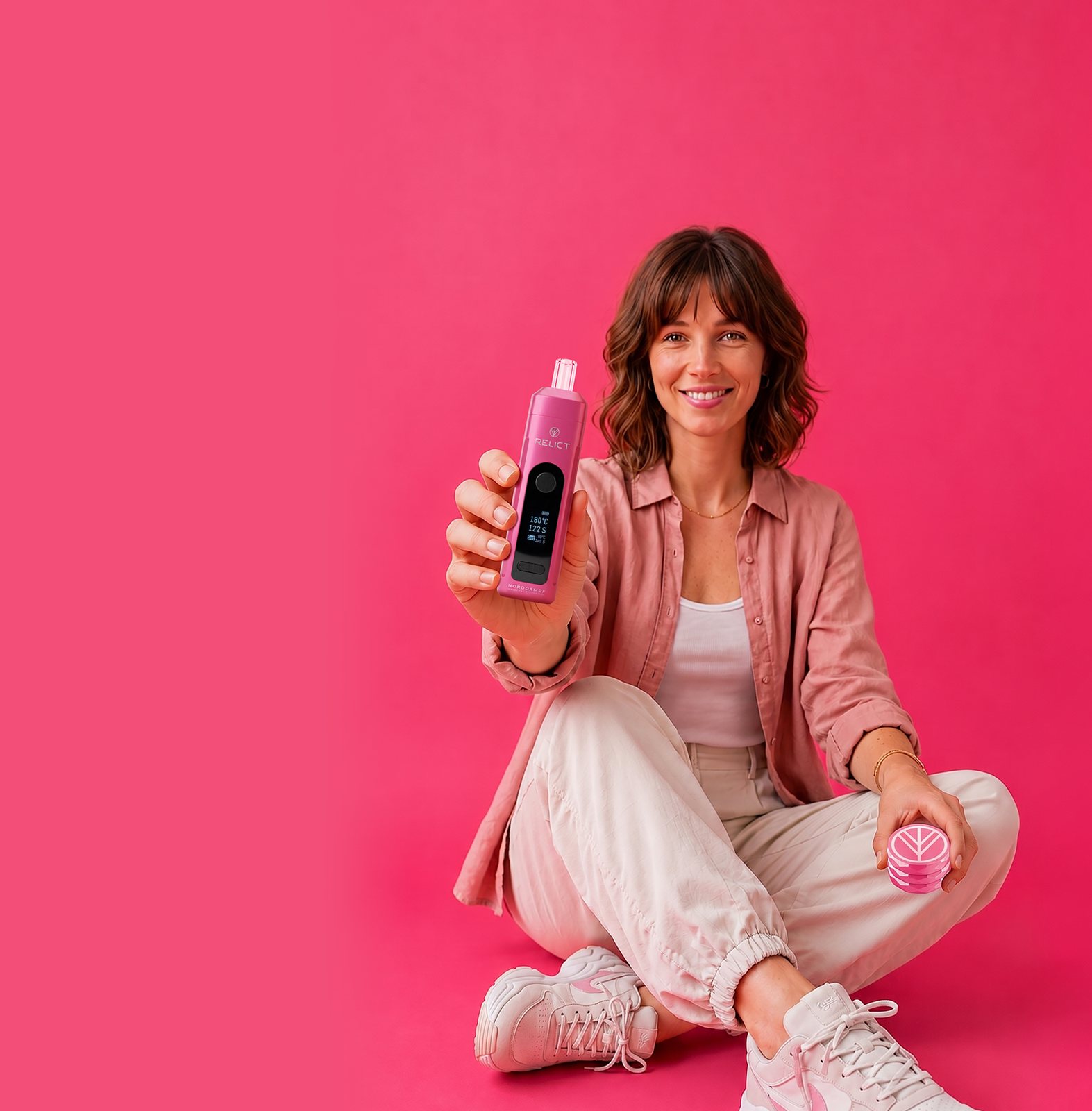 Frau mit RELICT Velvet Rose Vaporizer und Grinder vor pinkem Hintergrund