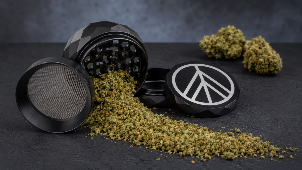 Gemahlene, mit HHC versetzte Cannabisblüte, die aus einem offenen schwarzen Grinder rieselt